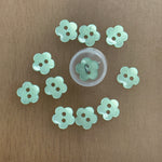 Mint green flower-shaped plastic buttons with two holes, arranged in a circle
