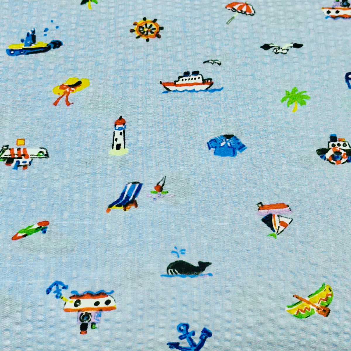 Light blue seersucker fabric with small nautical icons: boats, lighthouse, anchor, whale, sailor items.
