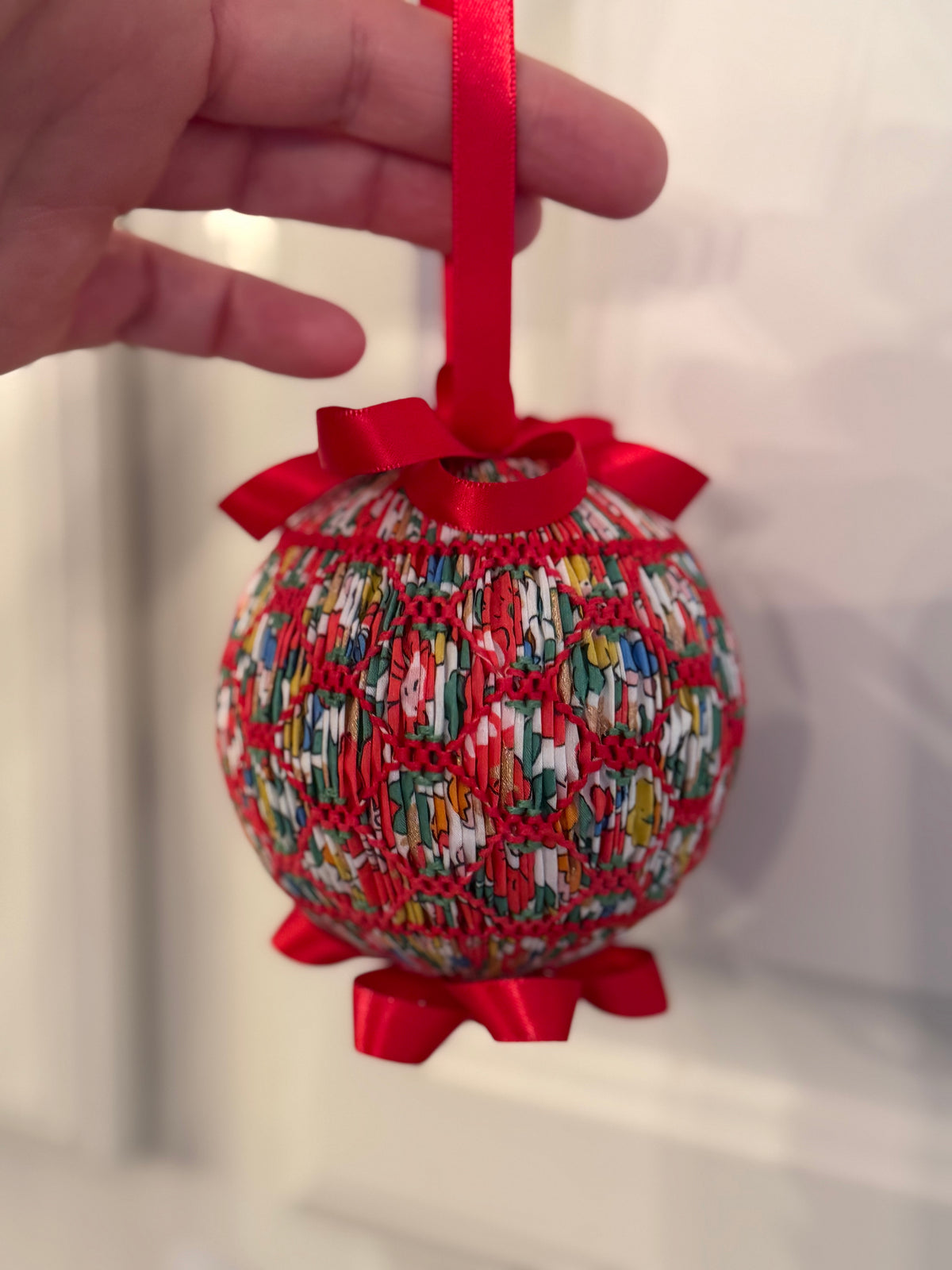 Smocked Christmas ornament ball in Liberty Tana Lawn fabric with red ribbon trim