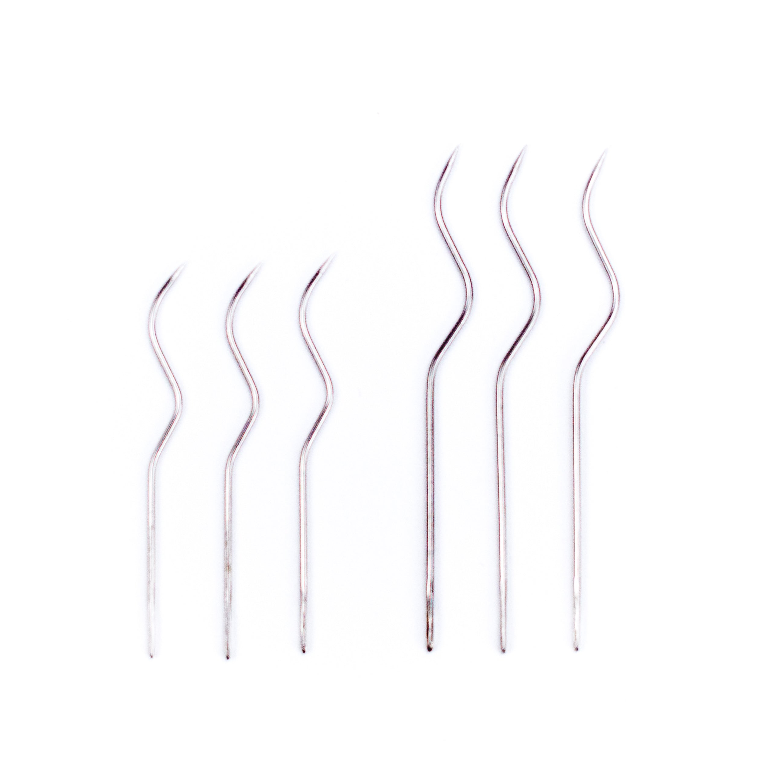 Six silver S-curved pleater needles arranged in a row on white background