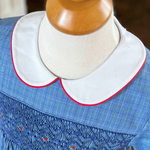 White pique peter pan collar with red piping on blue smocked dress form