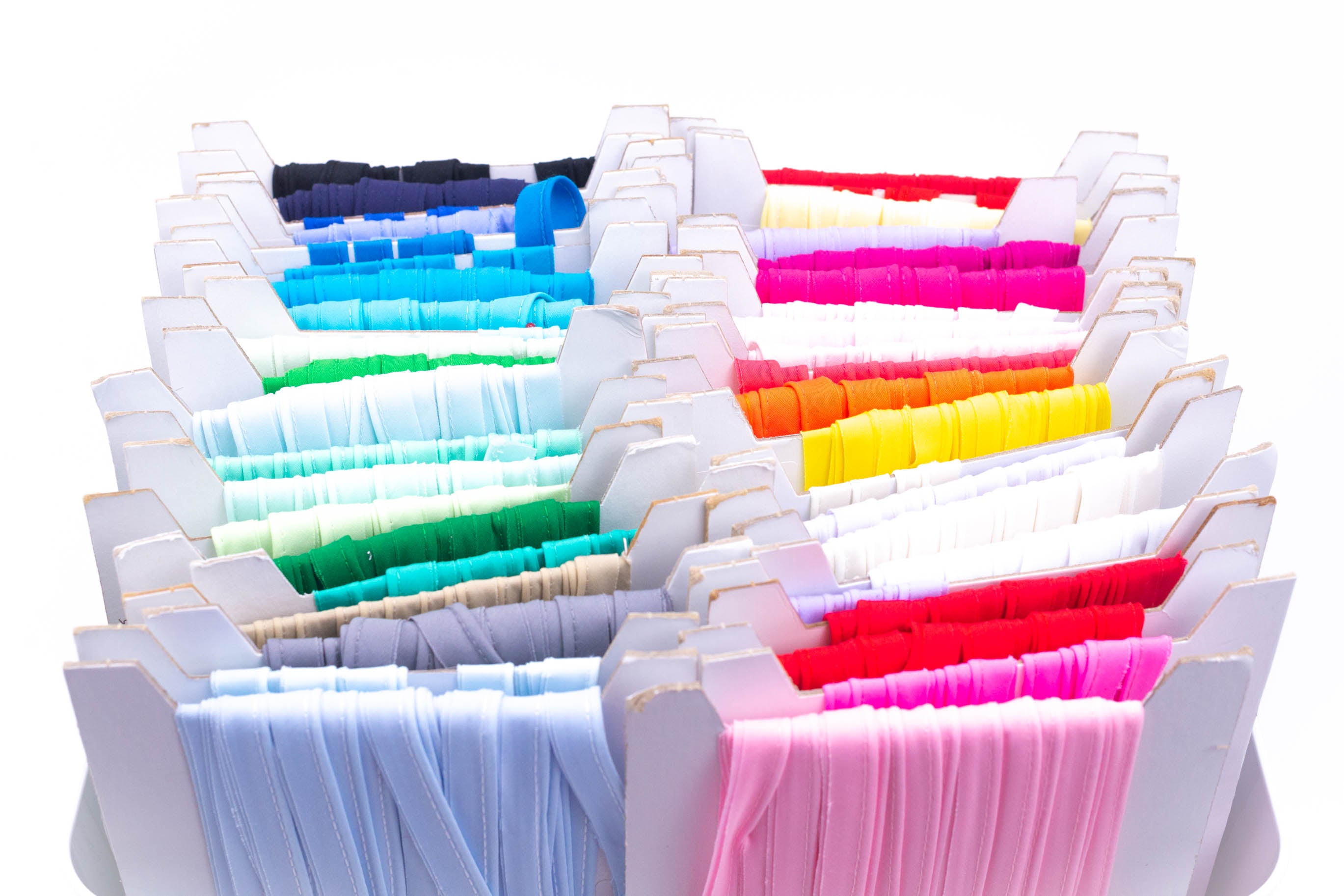 Solid piping trim in assorted colors displayed on white cardboard organizer slots.