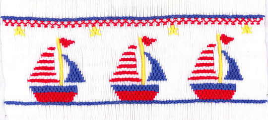 Smocking plate featuring three red, white, and blue sailboats with yellow stars on white fabric
