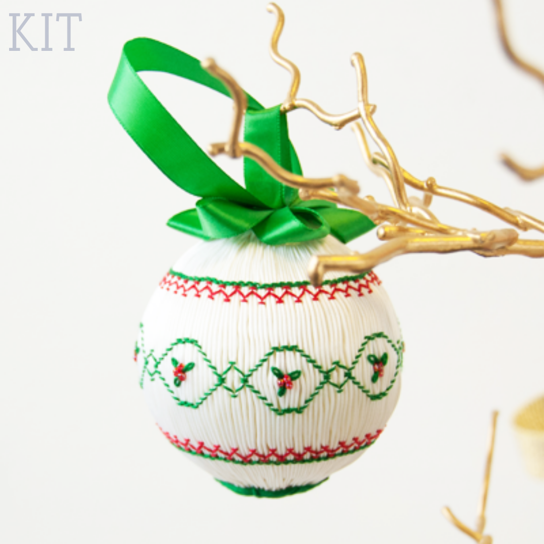 White smocked Christmas ornament with green and red holly embroidery and green satin ribbon